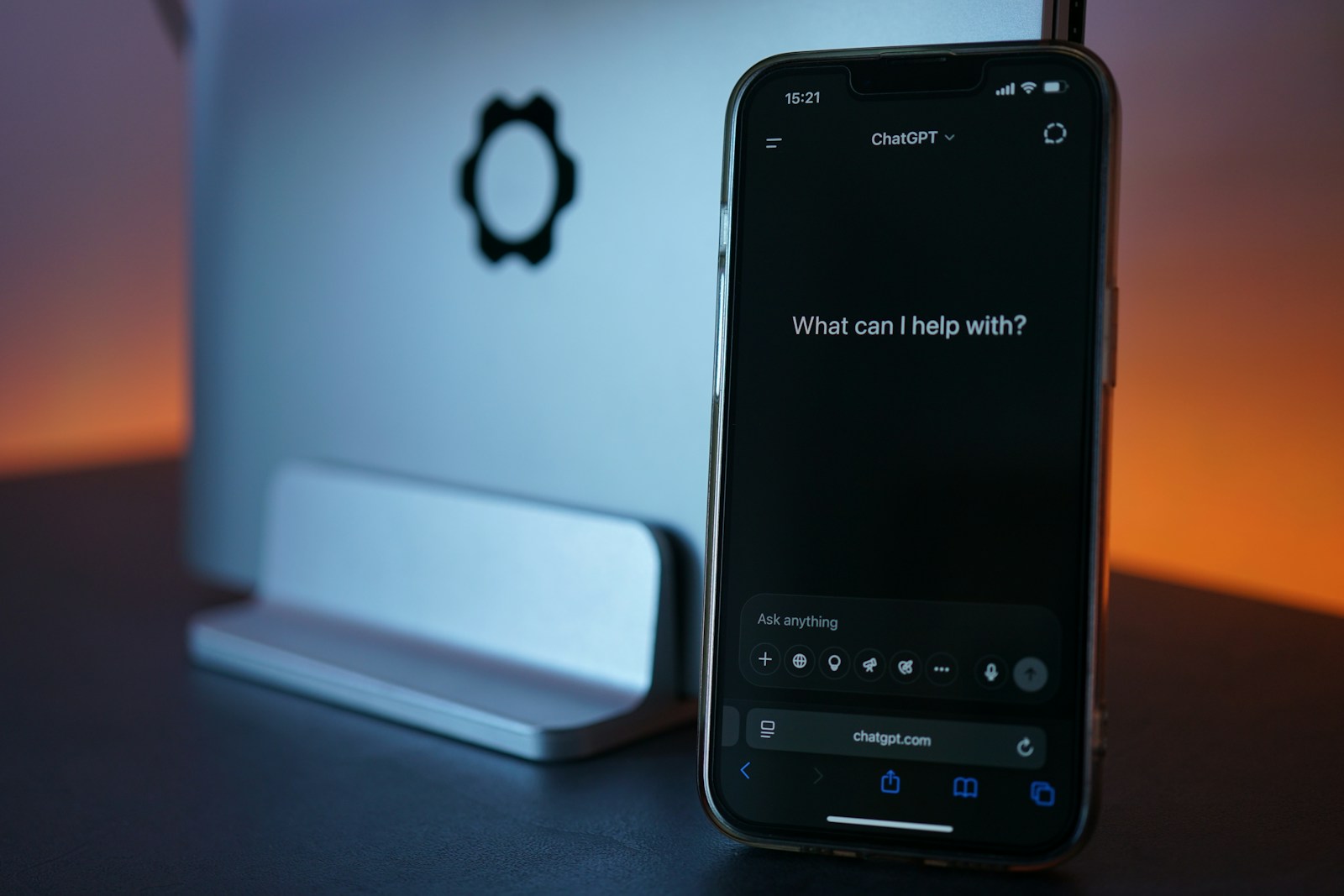 A phone displaying ChatGPT beside a laptop