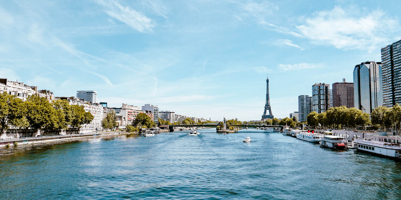 Boats on the Seine in Paris, with the Eiffel Tower beyond the riverbanks